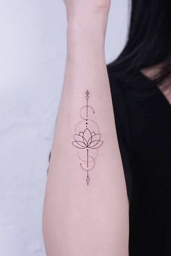 Minimalist lotus flower arm tattoo with geometric designs and dotwork, showing delicate ink art on a woman's forearm.