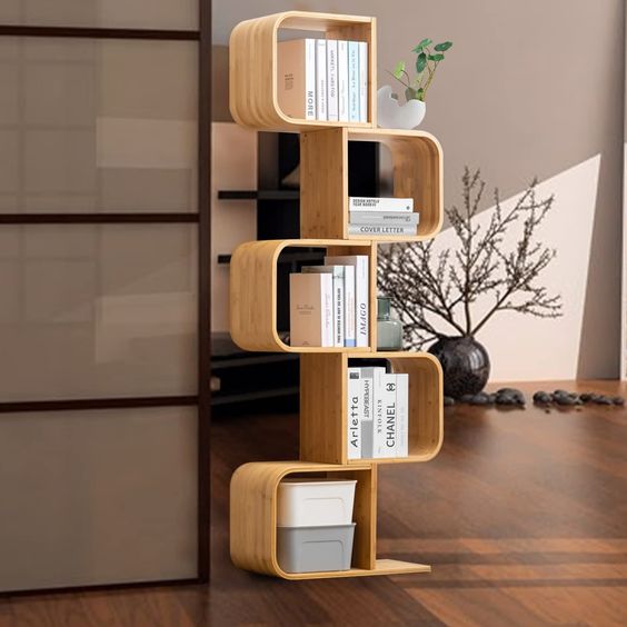 Modern S-shaped wooden bookshelf with books, decorations, and a potted plant in a minimalistic living room.