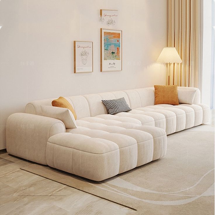 Modern living room with a beige sectional sofa, decorative pillows, framed art, floor lamp, and beige curtains.