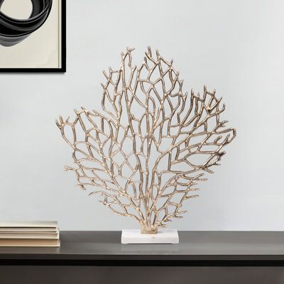 Decorative coral sculpture on a modern black table with books and framed wall art in a contemporary room setting.