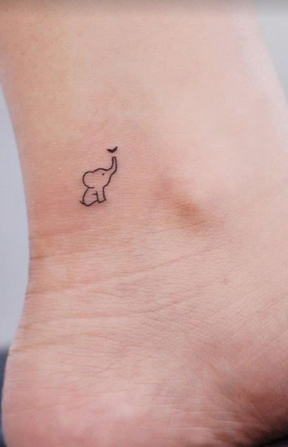 Minimalist elephant tattoo on ankle with the trunk raised, complementing the elegant design and accentuating ankle beauty.