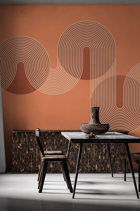 Modern dining room with a geometric wall mural, dark wooden table and chairs, and a decorative vase on the table.