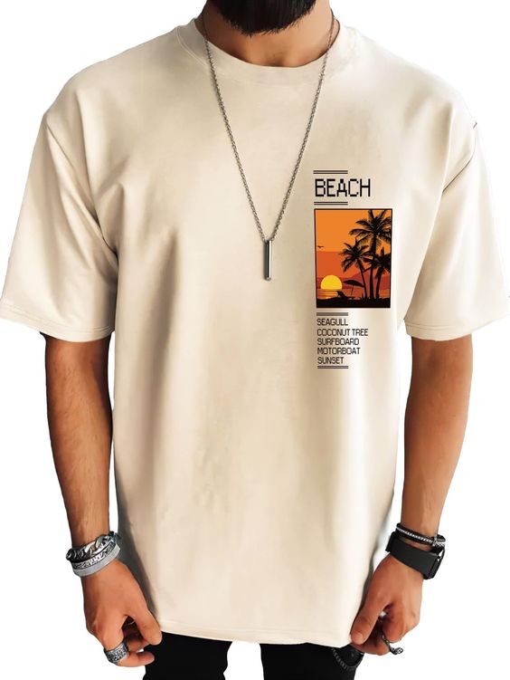 Man wearing a beige BEACH t-shirt with sunset, palm tree print, and keywords: Seagull, Coconut Tree, Surfboard, Motorboat, Sunset.