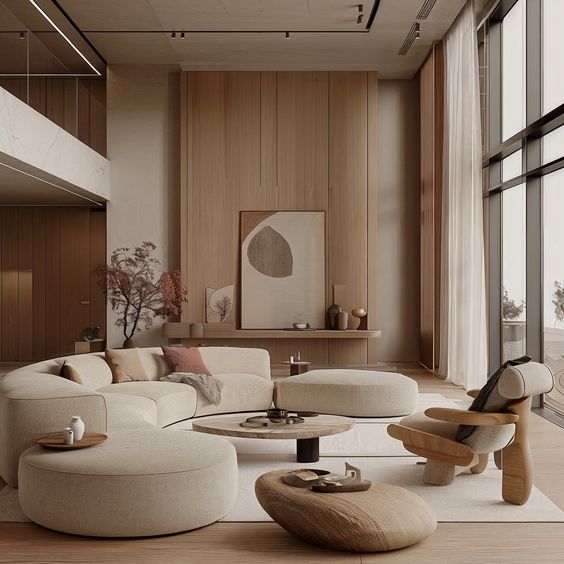 Modern living room with beige furniture, large windows, wooden paneling, and minimalist decor, featuring a cozy sectional sofa.