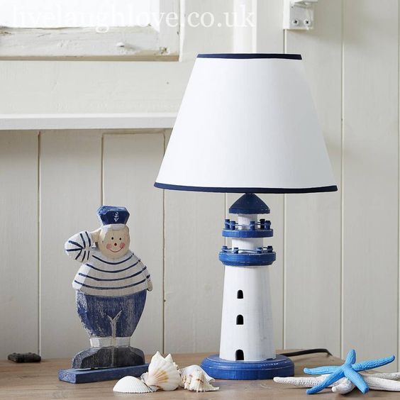 Nautical-themed table with lighthouse lamp, sailor figurine, seashells, and starfish decor. Coastal decor inspiration.