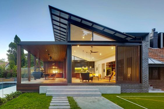 Modern home with spacious glass windows, outdoor patio, and lush green garden, featuring sleek architecture and open interior design.