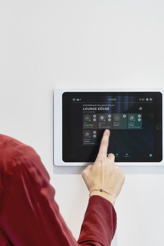 Person using a touchscreen smart home control panel for adjusting settings in a modern living space.