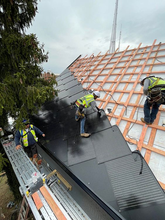 Workers installing solar panels on a roof, part of a renewable energy project under construction.