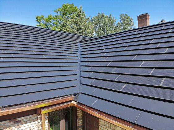 Modern house roof with sleek solar panels installed for energy efficiency and sustainability against a clear blue sky.