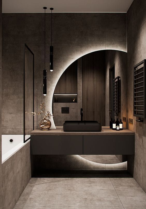 Modern bathroom interior with a black sink, circular mirror lighting, pendant lights, and minimalist decor elements.