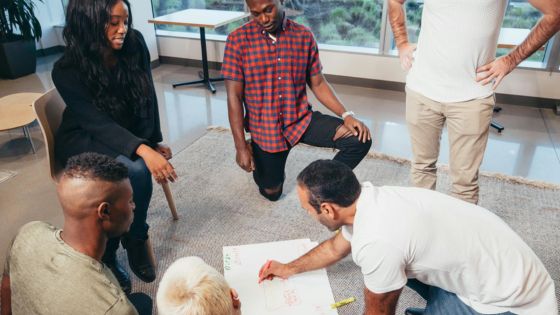 Diverse team engaged in brainstorming session, collaborating and sketching ideas on paper in a modern office environment.