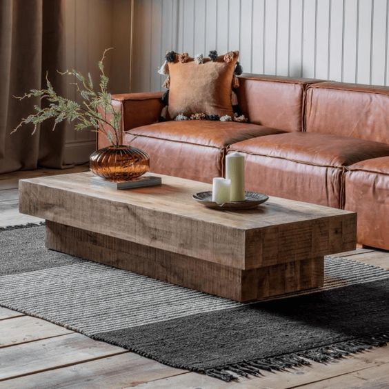 Modern rustic living room with a wooden coffee table, leather sofa, decorative vase, and cozy throw pillows.