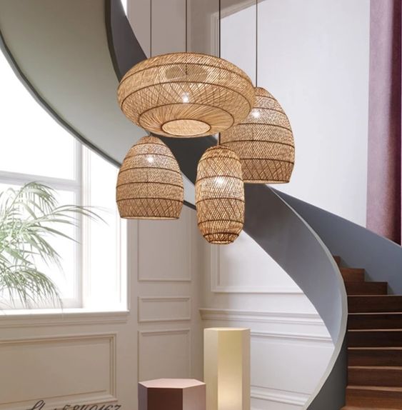 Modern pendant lights with woven rattan shades illuminate a stylish foyer with a spiral staircase and contemporary decor.