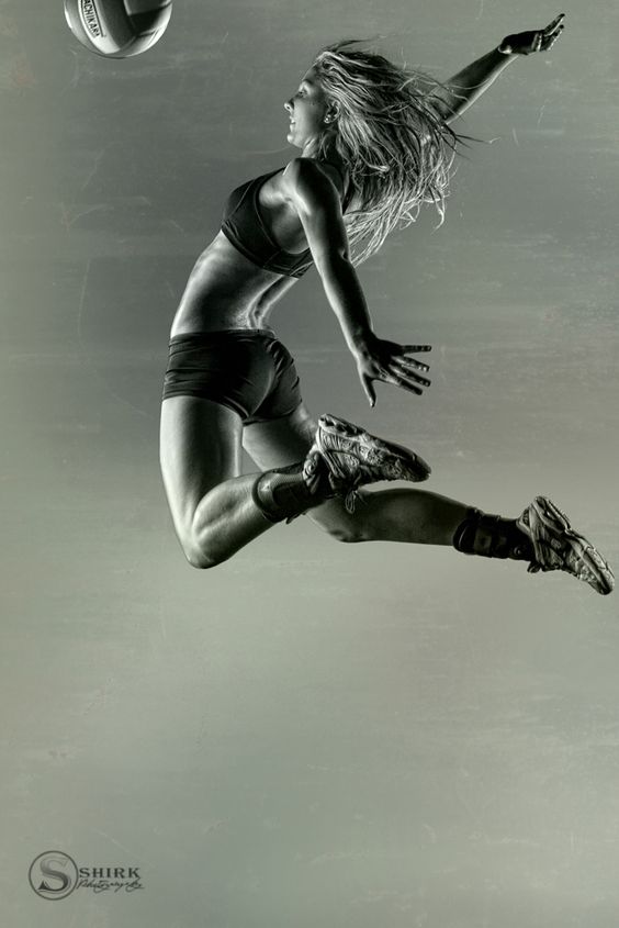 Female volleyball player in mid-air spike, powerful athletic pose, dynamic motion. Photo by Shirk Photography.