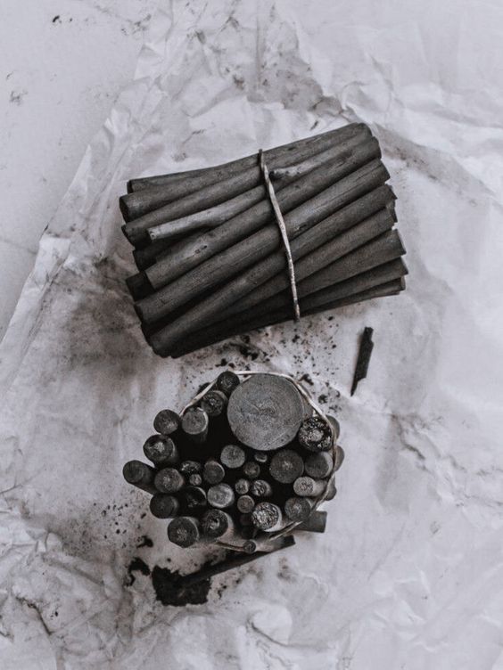 Charcoal sticks neatly bundled on crumpled white paper, perfect for artistic sketching or detailed shading.