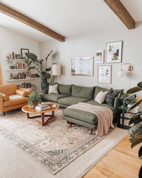 Cozy living room with green sofa, yellow armchair, wooden coffee table, plant decor, bookshelves, and wall art in a modern design.