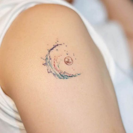 Close-up of a forearm tattoo featuring a watercolor wave and crescent moon, blending artistic elements in a minimalist design.