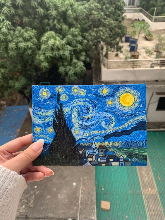 Person holding a miniature painting inspired by Starry Night by Van Gogh with an outdoor background.