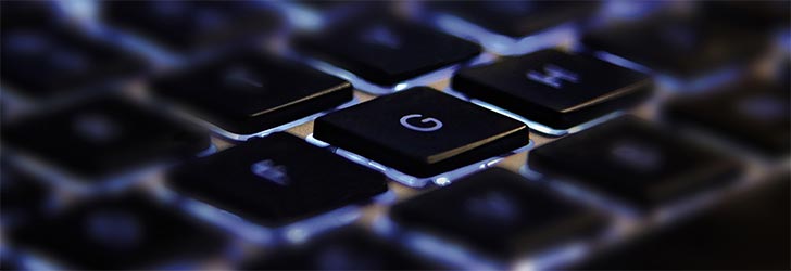 Close-up view of illuminated computer keyboard keys, focusing on the 'G' key, highlighting technology and typing concepts.