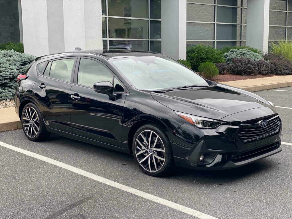 Black Subaru Impreza parked outside modern building, showcasing sleek design and alloy wheels.