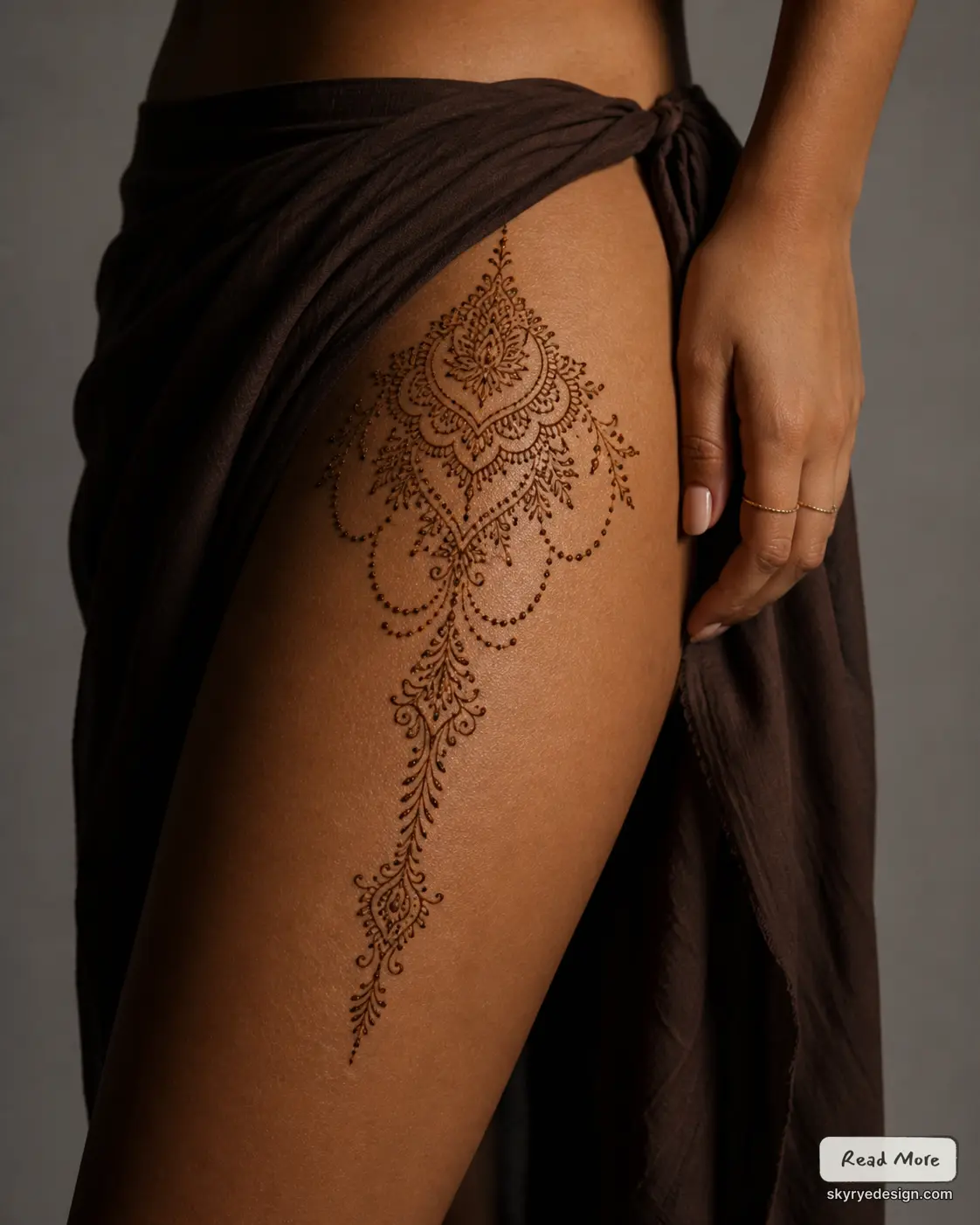 Intricate henna (mehndi) thigh tattoo on model, cascading mandala and floral lace design with dark sarong — boho body art