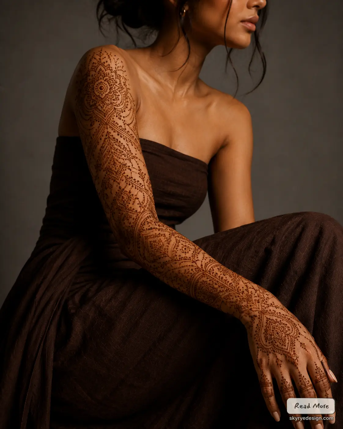 Intricate full-arm henna (mehndi) sleeve on woman wearing a dark strapless dress, ornate bridal-style henna design