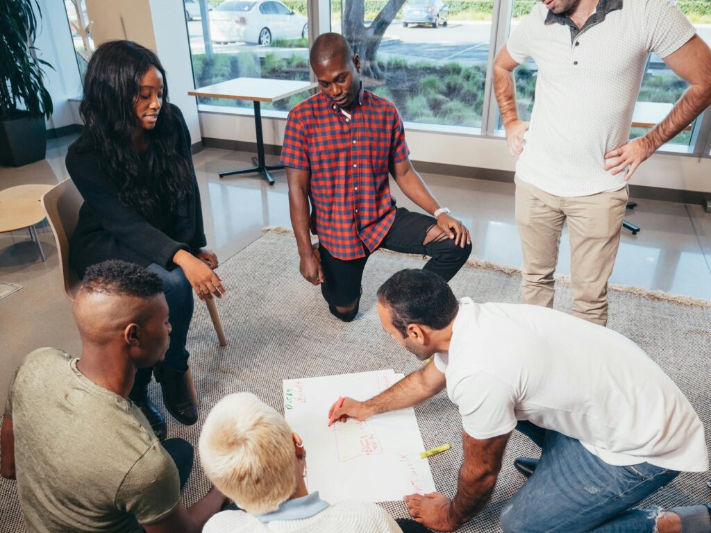 Group of diverse colleagues brainstorming and collaborating on a project while writing ideas on a large paper in an office.