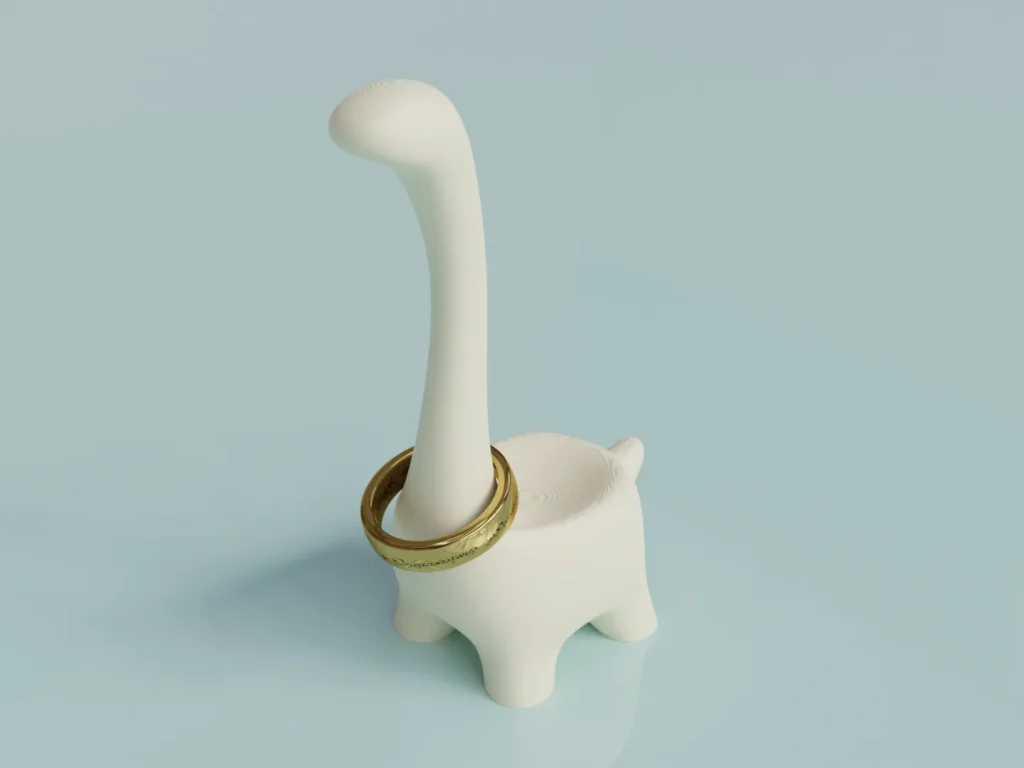 White dinosaur-shaped ring holder with a gold ring around its neck on a light blue background.