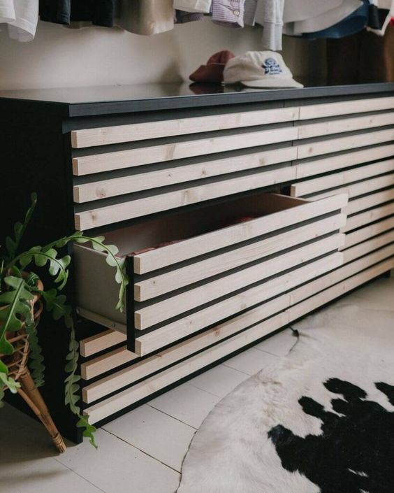 Modern wooden dresser with a drawer open, set in a cozy room featuring a potted plant and a cowhide rug.