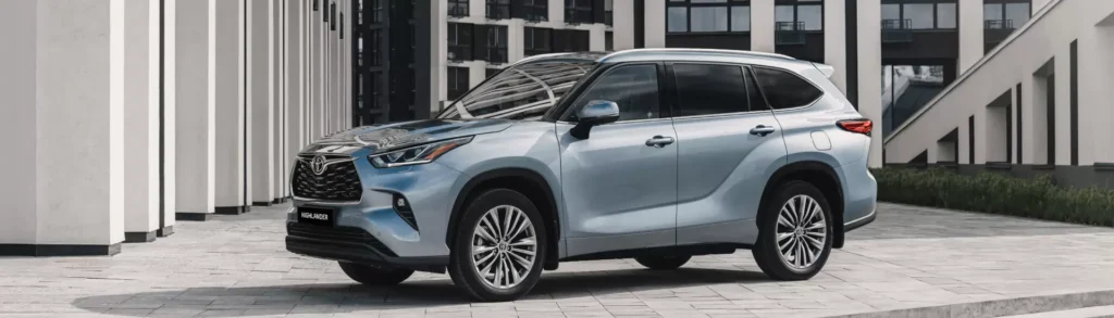 Silver 2023 Toyota Highlander parked in a modern urban setting, showcasing sleek design and advanced features.