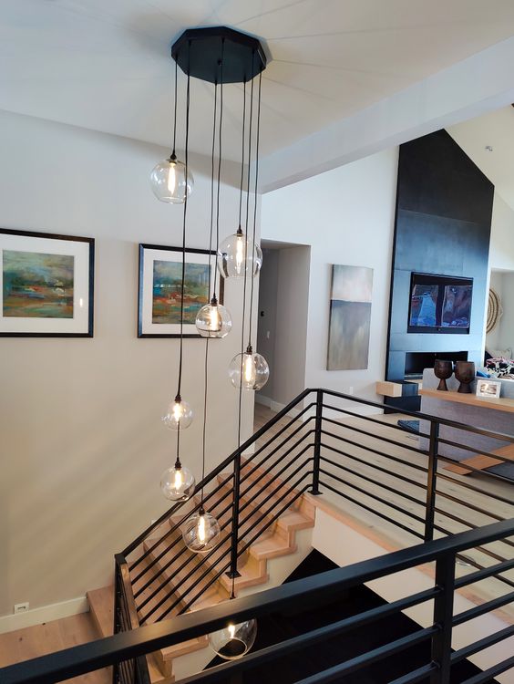 Modern hanging lights in a stylish, contemporary living room with staircase, abstract wall art, and elegant decor.