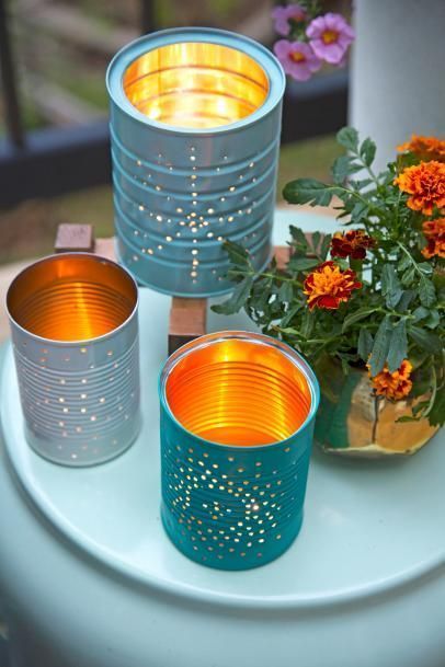 Colorful DIY tin can lanterns and a pot of marigolds on a table, creating a cozy outdoor ambiance.