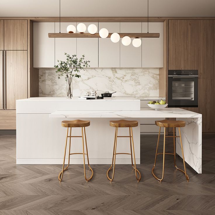 Modern kitchen with white marble countertops, wooden cupboards, gold bar stools, and elegant hanging lights.