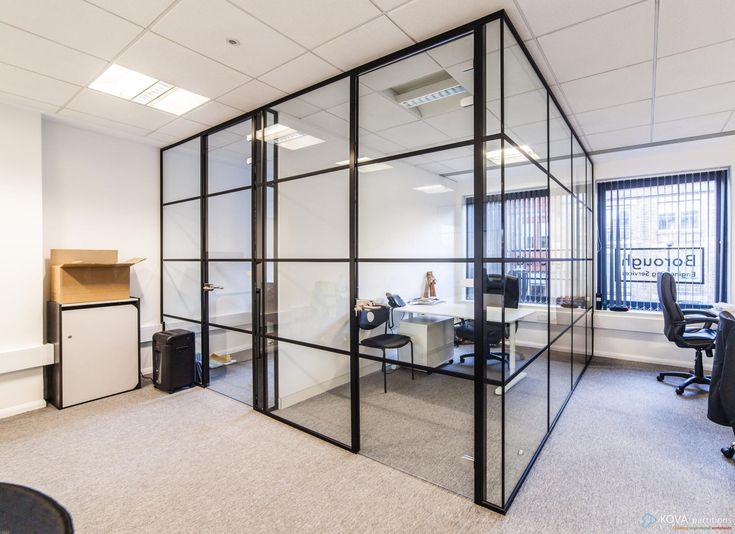 Modern office with glass partitions, desks, and chairs, featuring a minimalist design and ample natural light.