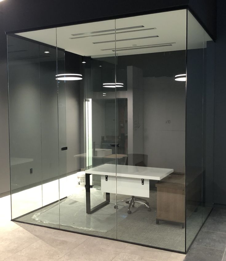 Glass-walled office space with a modern white desk, swivel chair, and ambient lighting, perfect for productivity and privacy.