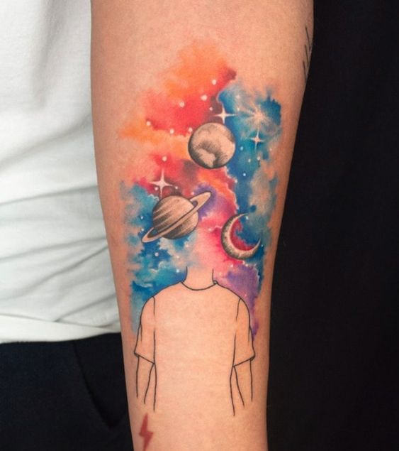 Colorful space-themed tattoo on arm with planets and stars, head replaced by celestial imagery, vibrant cosmic design.