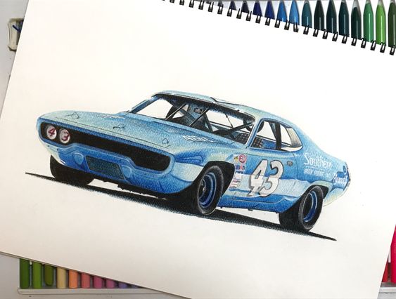 Drawing of a classic blue race car with the number 43, displayed on an open sketchbook with colored pencils in the background.