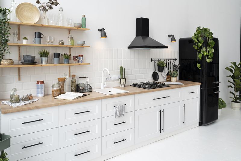 Modern kitchen with white cabinets, wooden countertops, black appliances, open shelves, and indoor plants.