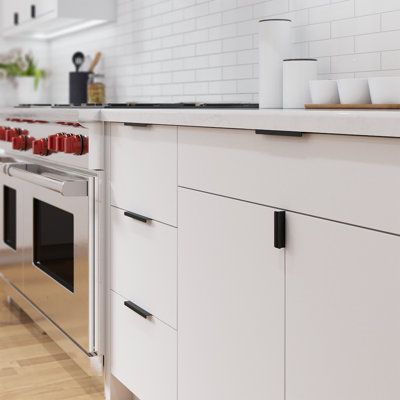 Modern kitchen with sleek white cabinets, stainless steel stove, and red knobs; featuring clean design and minimalist décor.