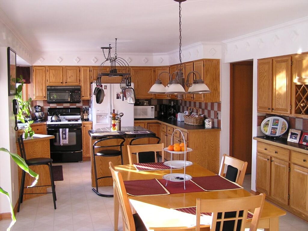 Bright, spacious kitchen with oak cabinets, an island, dining table, and modern appliances. Cozy and inviting cooking space.