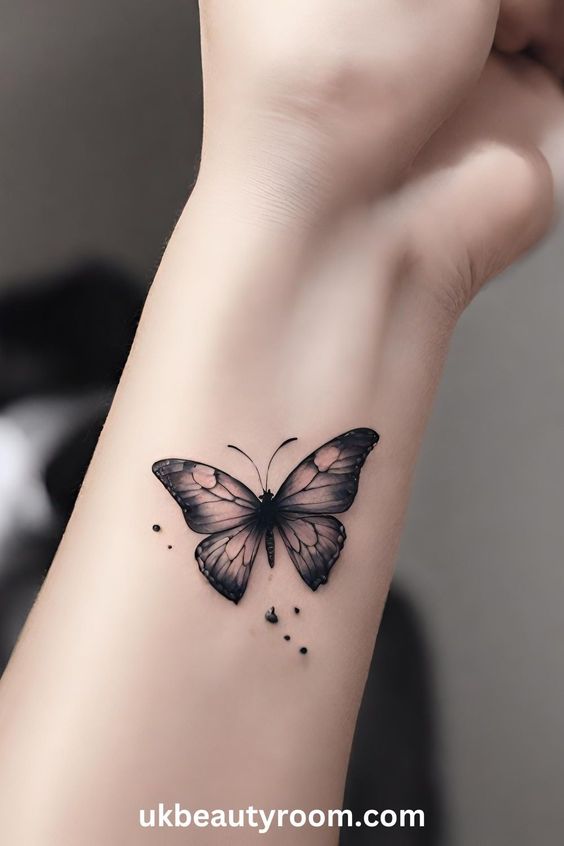 Butterfly tattoo on a wrist with delicate black and pink wings, showcasing intricate details and small dotted accents.