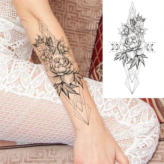 Elegant floral forearm tattoo design with geometric elements shown on a lace-dressed arm.