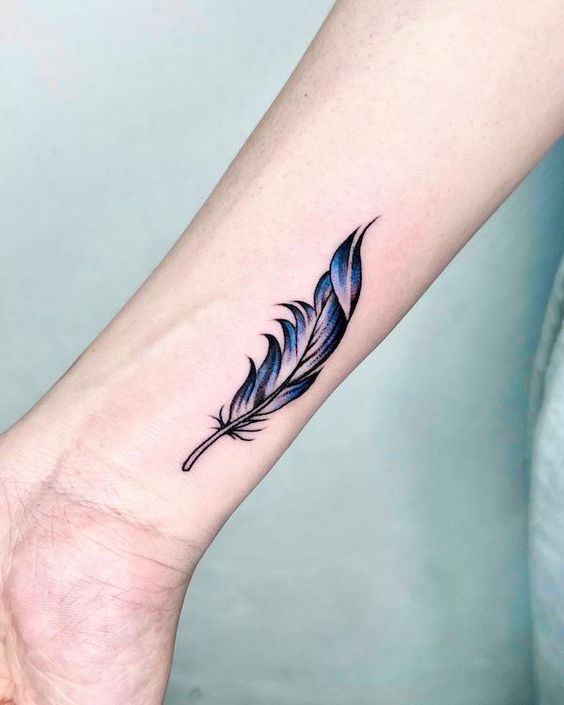 Minimalist feather tattoo in blue and black ink on forearm, symbolizing freedom and lightness.