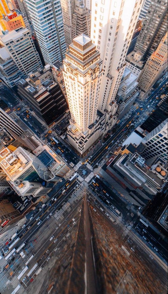 Aerial view of New York City skyscrapers and bustling streets at a busy intersection on a bright, sunny day.