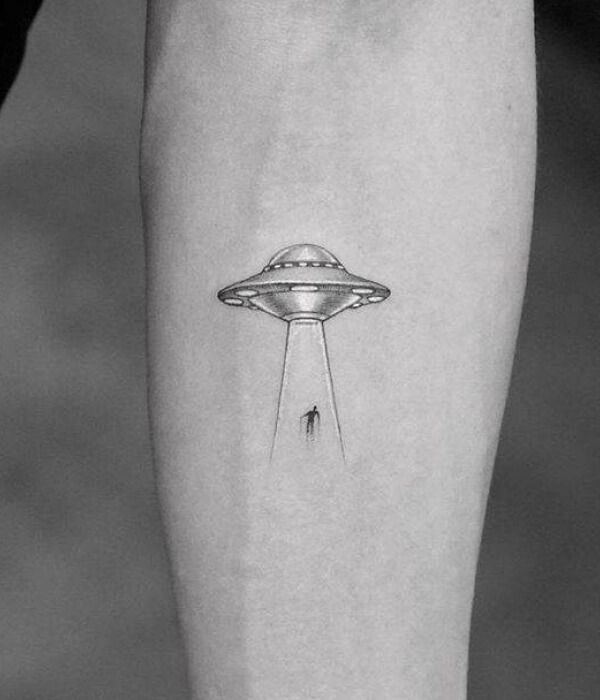 UFO tattoo on forearm depicting a flying saucer abducting a person with its beam of light.