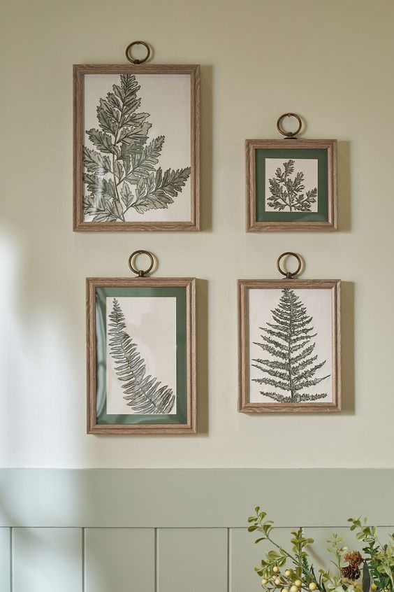 Framed botanical prints of fern leaves decorate a light green wall, adding a touch of nature-inspired elegance.