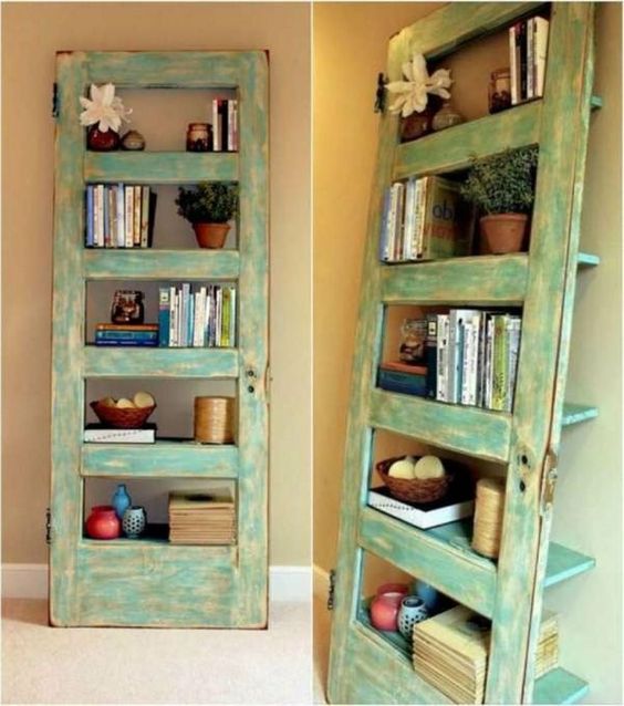 Vintage turquoise DIY bookshelf made from an old door, decorated with books, plants, and colorful vases in a cozy corner.