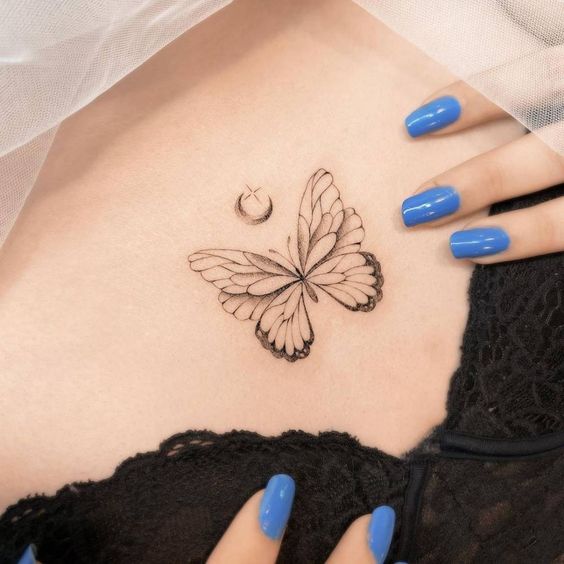 Butterfly tattoo on skin with vibrant blue manicured nails, lace fabric visible. Minimalist and delicate tattoo design.