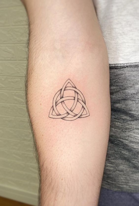 Minimalist Triquetra tattoo on inner forearm, symbolizing unity, eternity, and Celtic heritage. Black ink, intricate design.