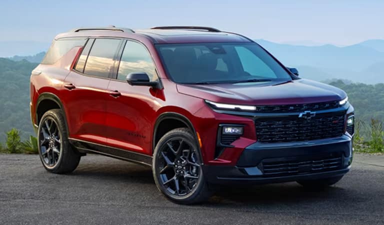 Red SUV parked on a scenic mountain road, featuring sleek black wheels and modern design. Perfect for adventure and family trips.